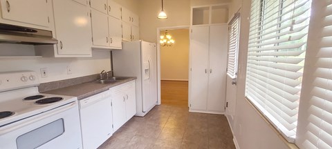 A kitchen with white cabinets and appliances.